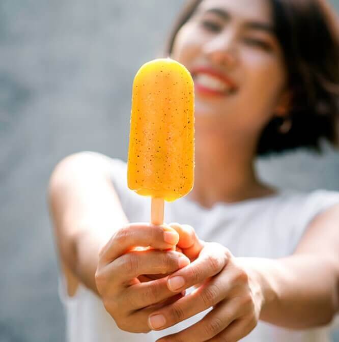 Woman holding orange ice pop