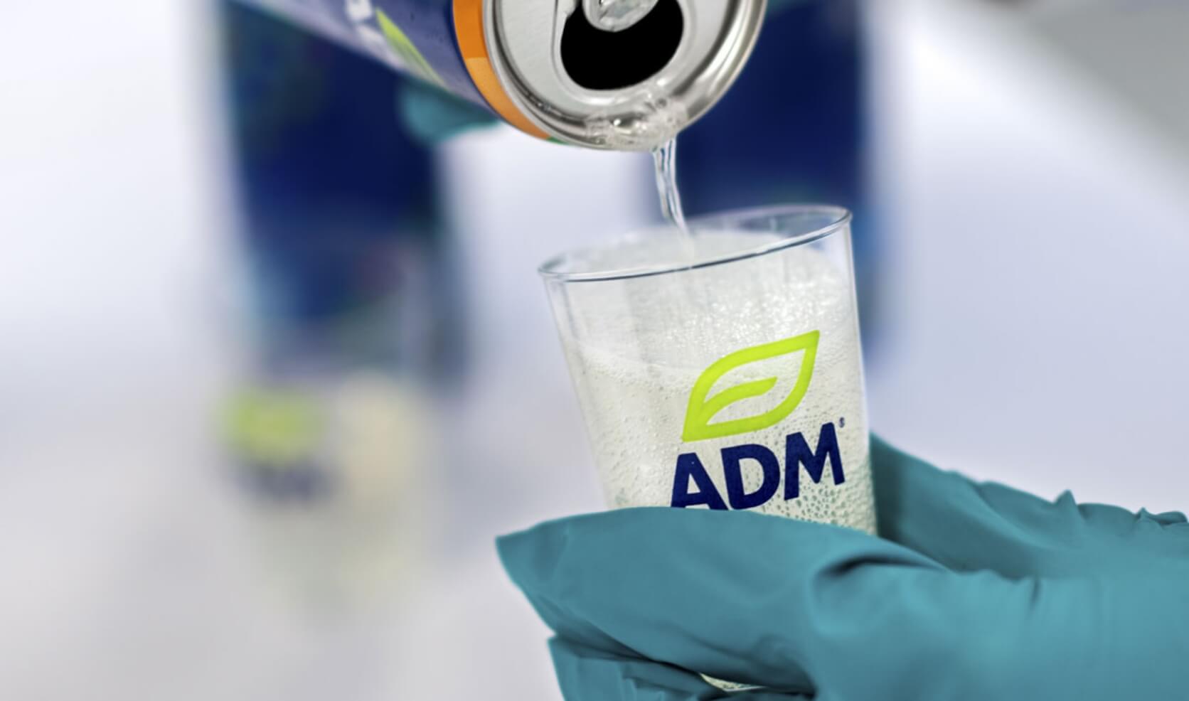 Can being poured into a small glass with ADM logo on it.